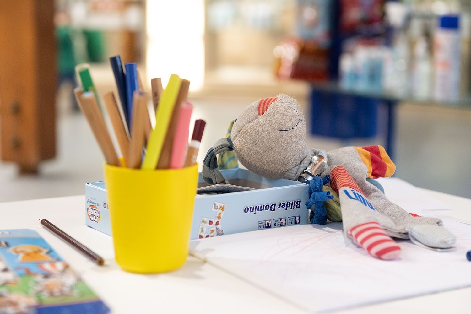 Auf einem Tisch steht ein gelber Becher voller Bleistifte und ein Stofftier.