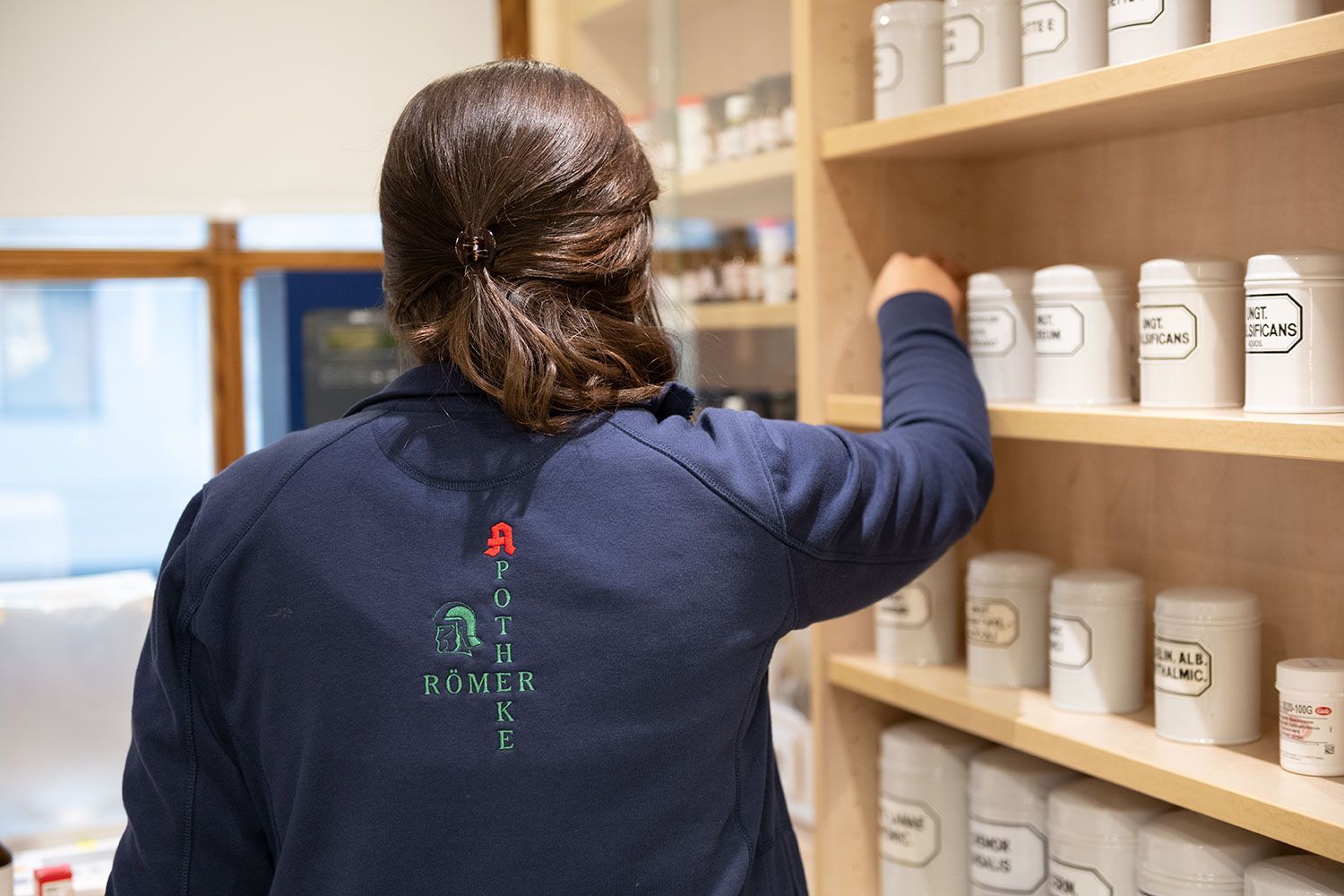 Eine Frau steht vor einem Regal in einer Apotheke.