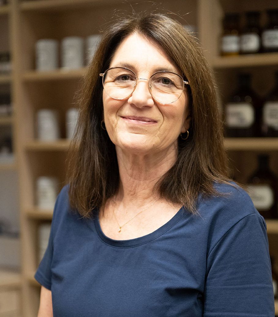 Eine Frau mit Brille und blauem Hemd lächelt in die Kamera.