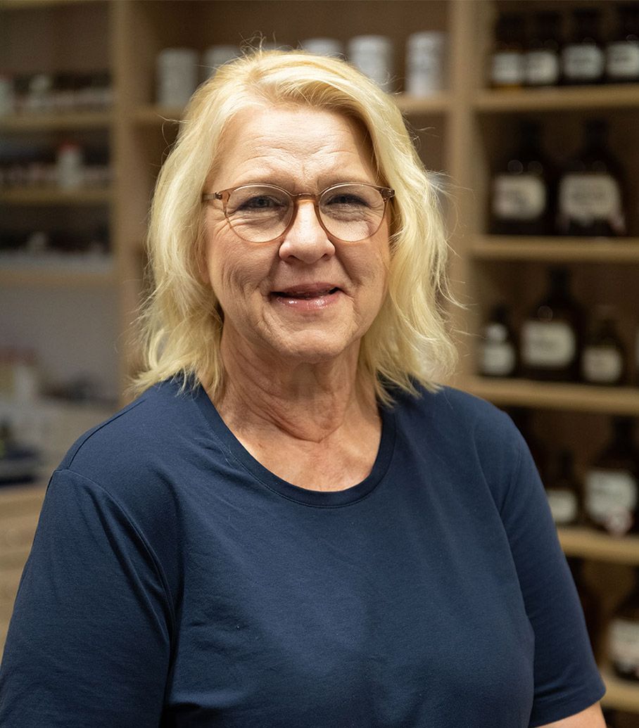 Eine Frau mit Brille und blauem Hemd lächelt in die Kamera.