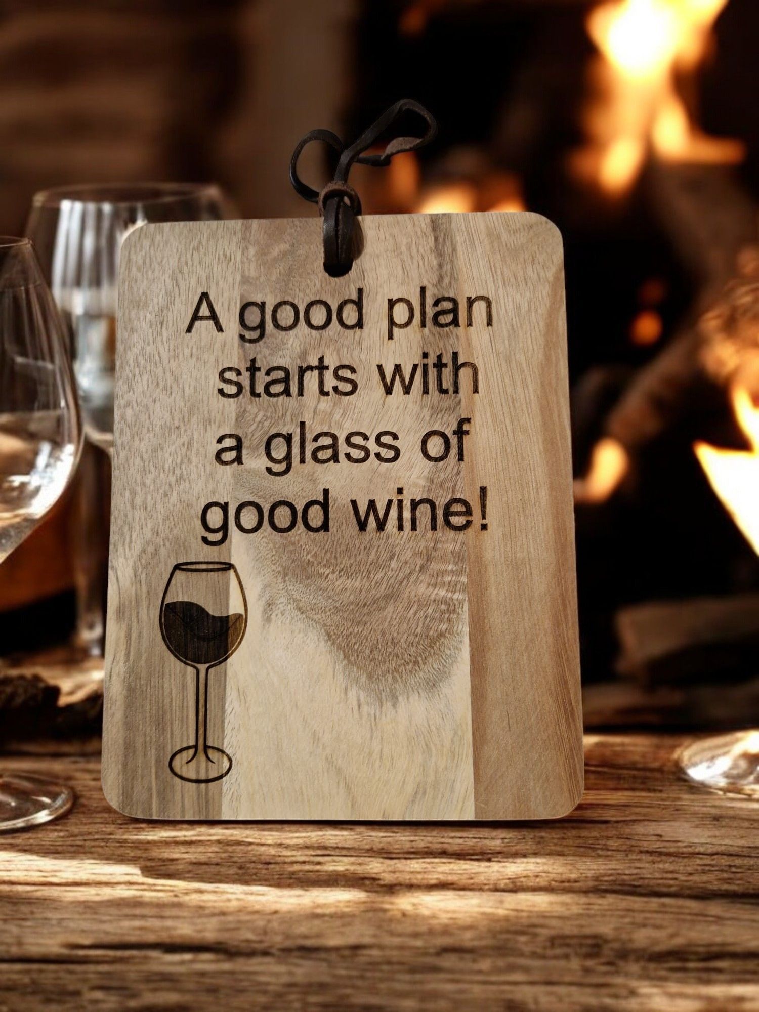 A wooden sign that says `` a good plan starts with a glass of good wine '' is sitting on a wooden table.