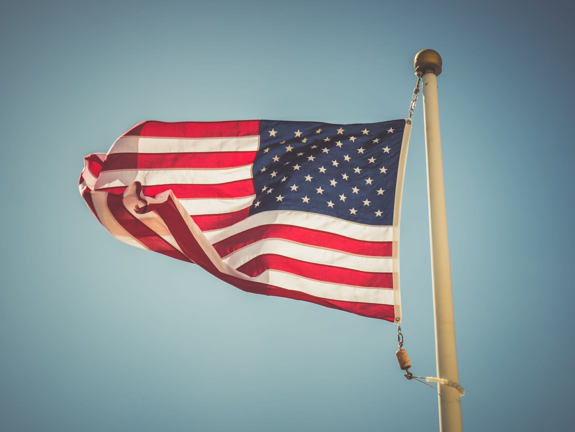 American flag waving on a pole against a clear blue sky