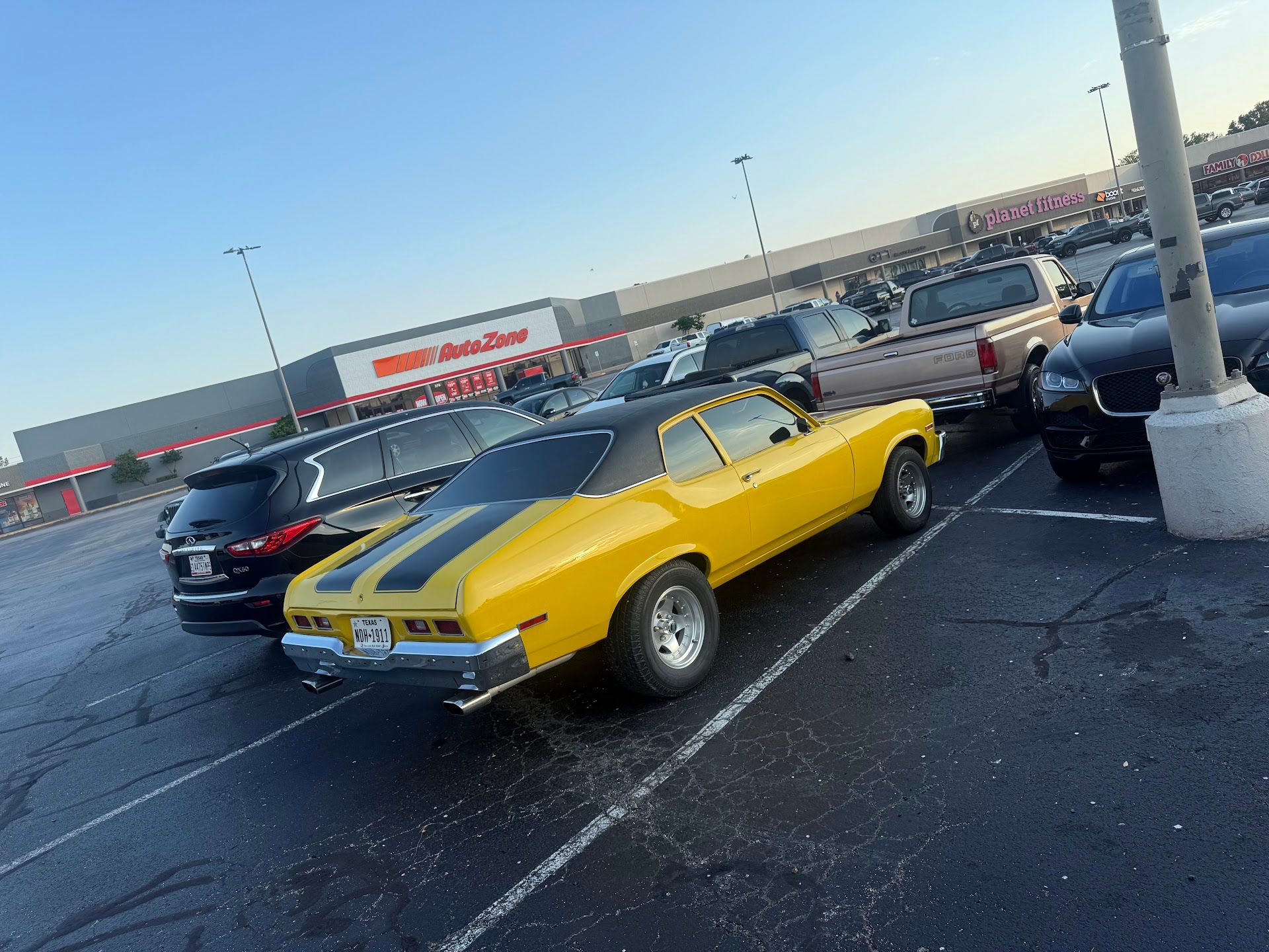 Yellow classic car with black stripes parked in a parking lot, near an AutoZone store. | El Dorado Shell