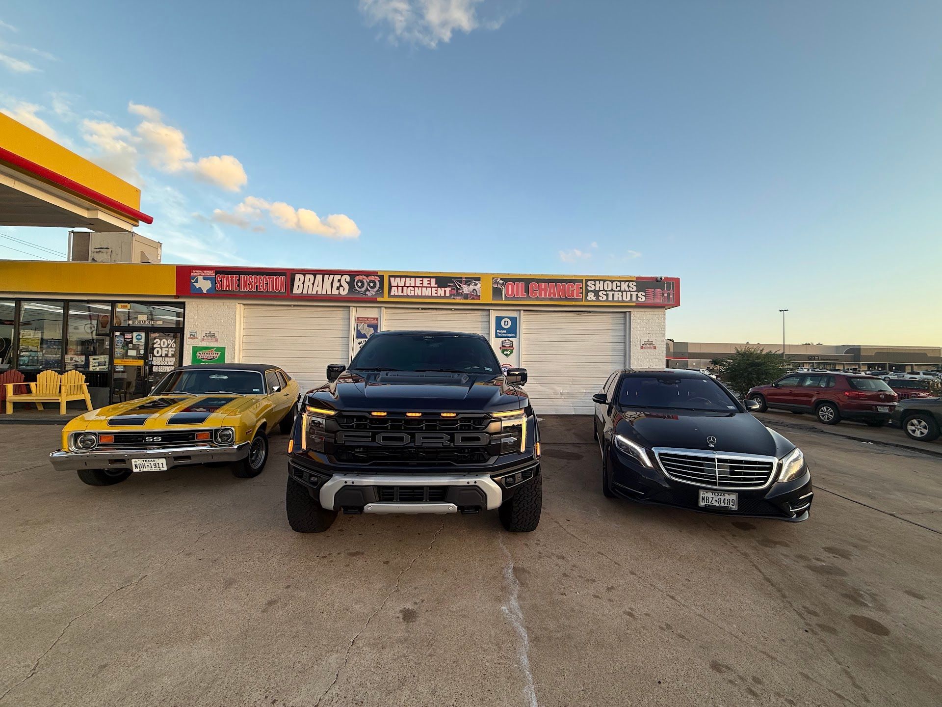 Three cars parked in front of a gas station: yellow muscle car, black truck, and black sedan. | El Dorado Shell