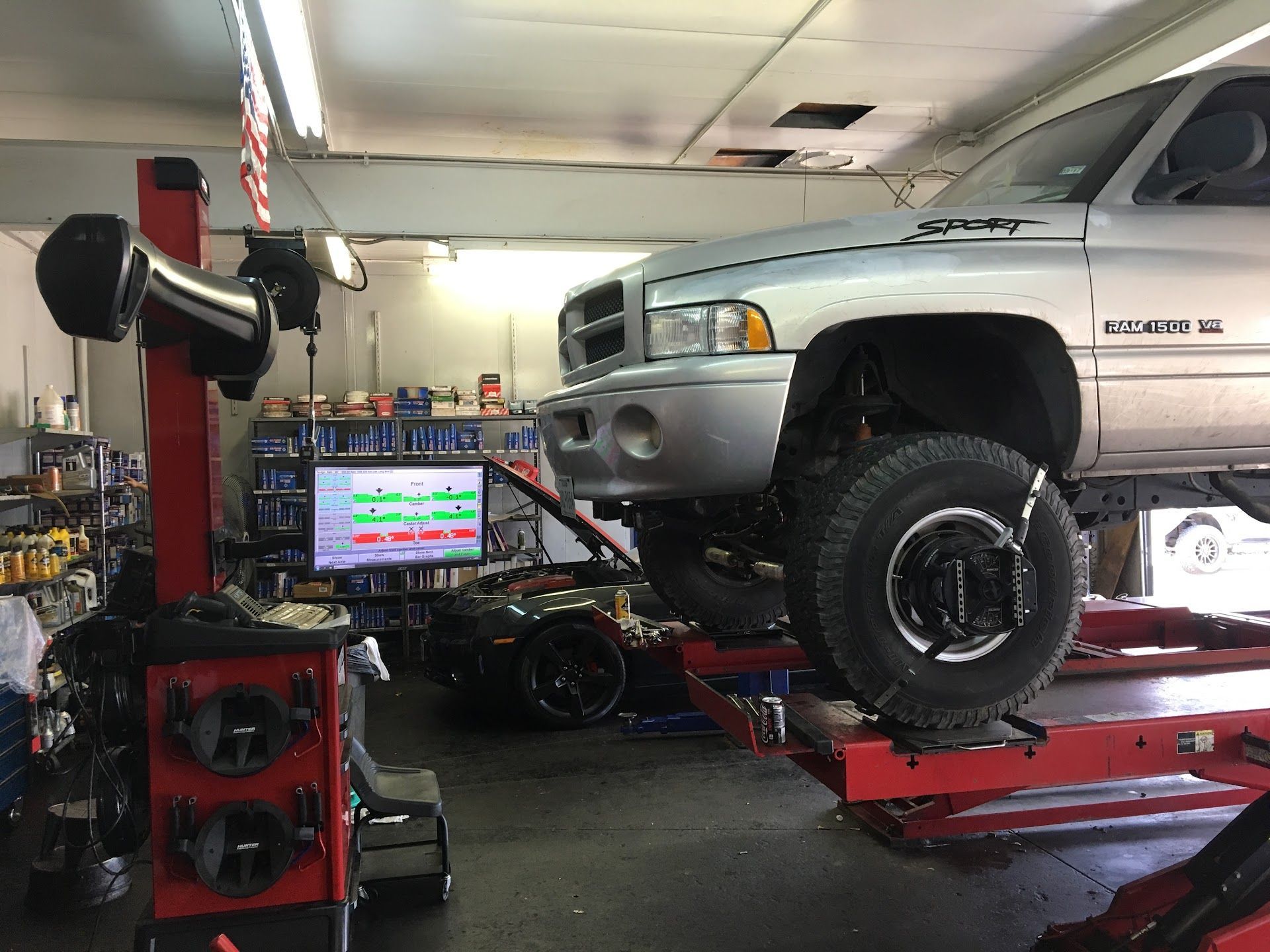 Silver truck raised on a lift in a shop, undergoing wheel alignment. Alignment equipment in view. | El Dorado Shell