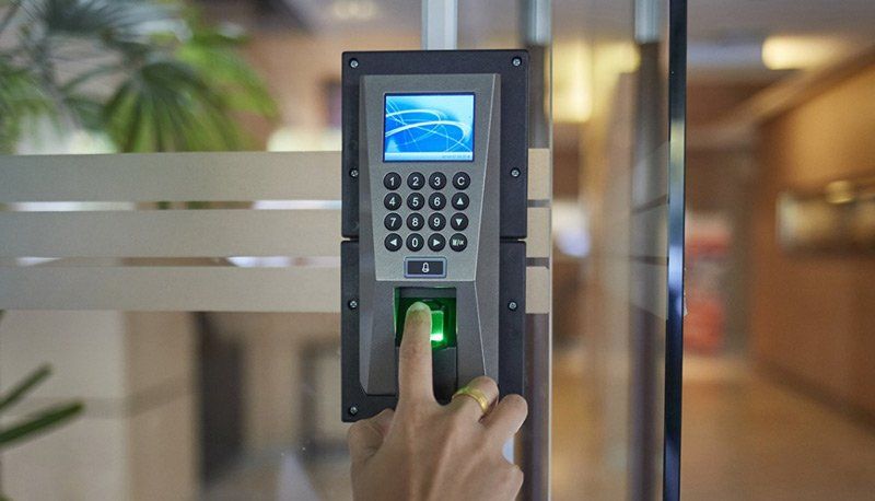 A person is using a fingerprint scanner to open a glass door.
