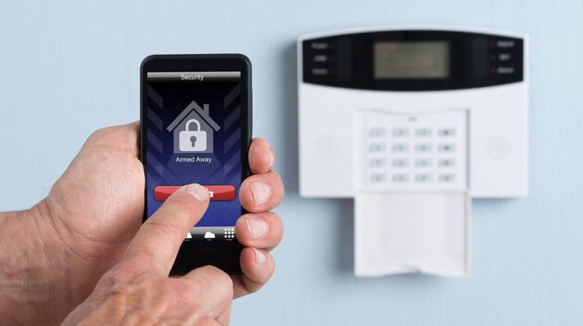 A person is holding a cell phone in front of a security system.