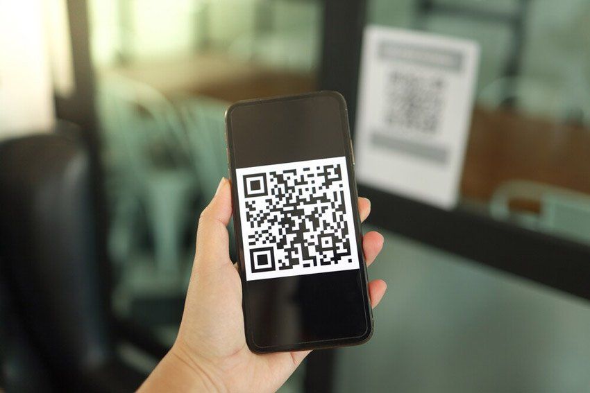 A person is holding a cell phone with a qr code on it.