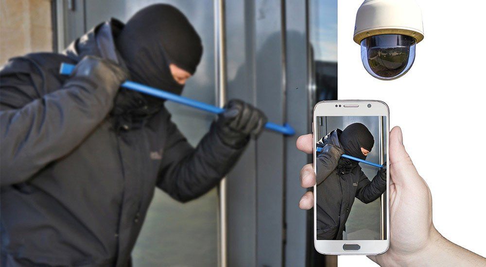 A person is holding a cell phone with a picture of a burglar on it