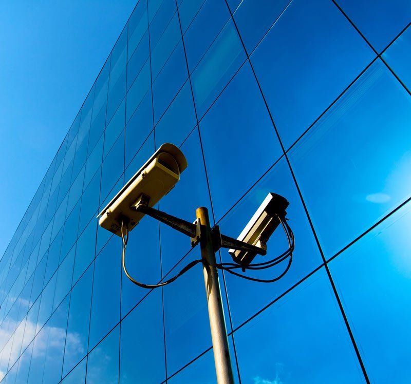 Two security cameras on a pole in front of a building