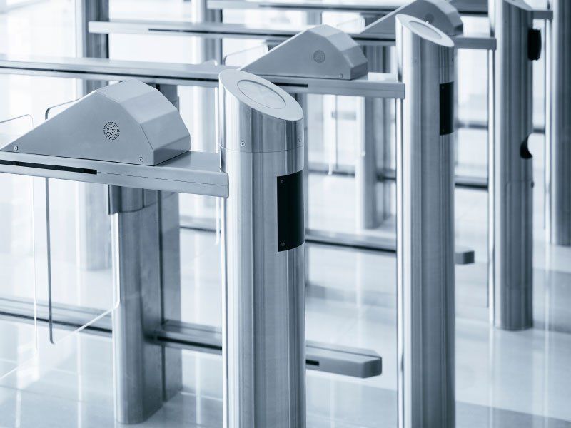 A row of stainless steel turnstiles in a building.