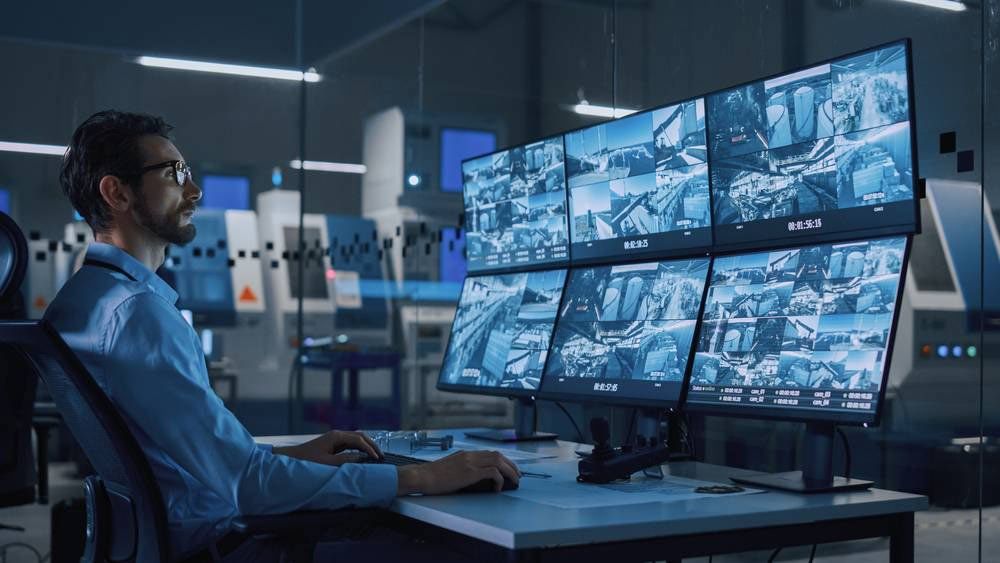 A man is sitting at a desk in front of a bunch of monitors.