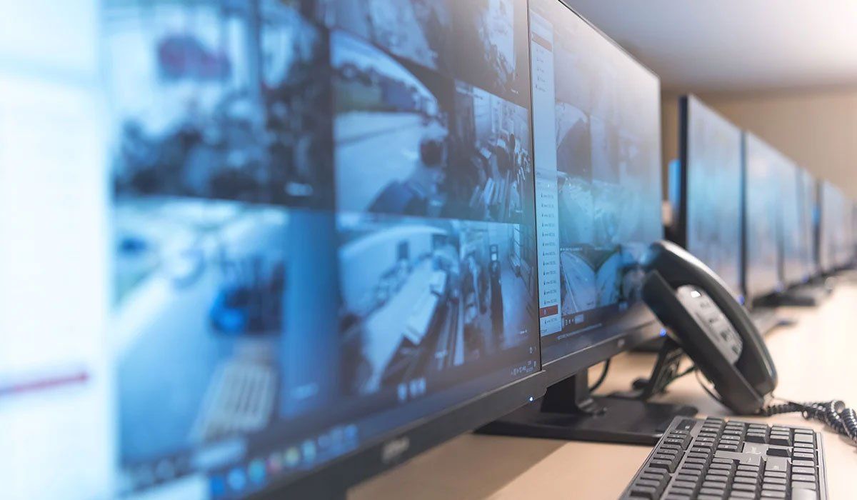 A row of computer monitors sitting on top of a desk.