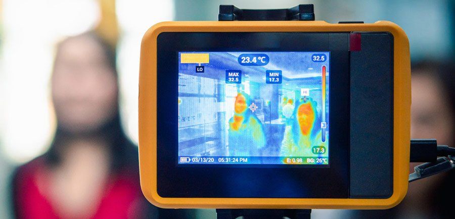 A thermal camera is taking a picture of a person 's temperature.