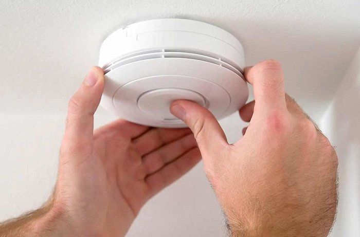 A person is installing a smoke detector on the ceiling.