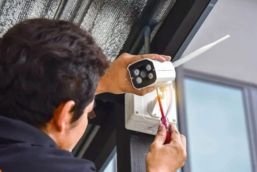 A man is installing a security camera with a screwdriver.