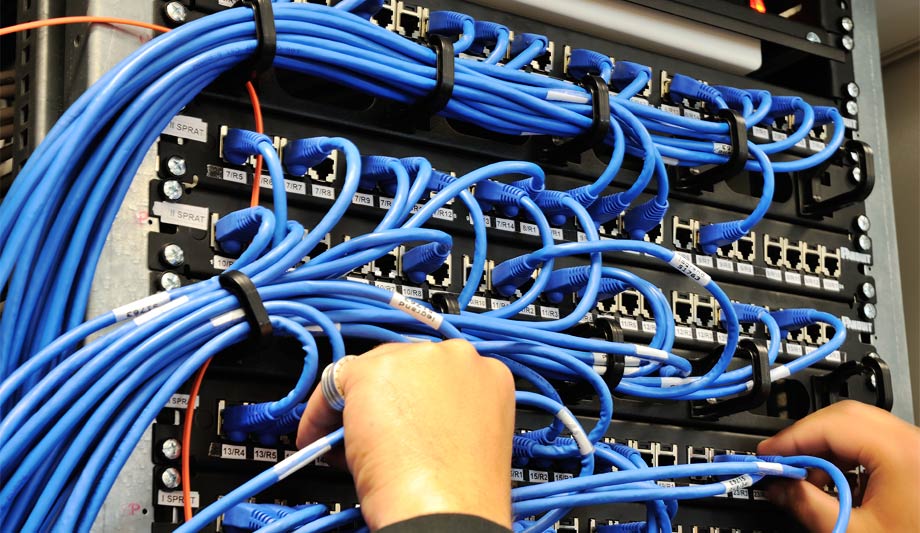 A person is working on a server with blue wires