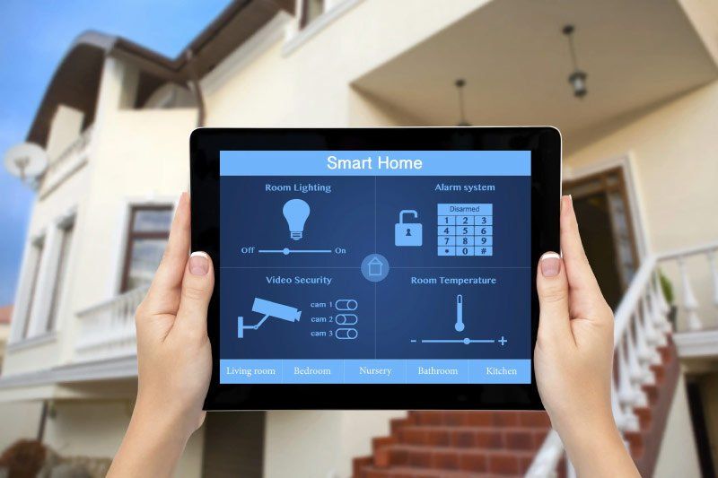 A person is holding a tablet in front of a smart home