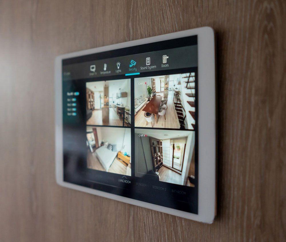 A tablet is hanging on a wooden wall and shows four pictures of a house.