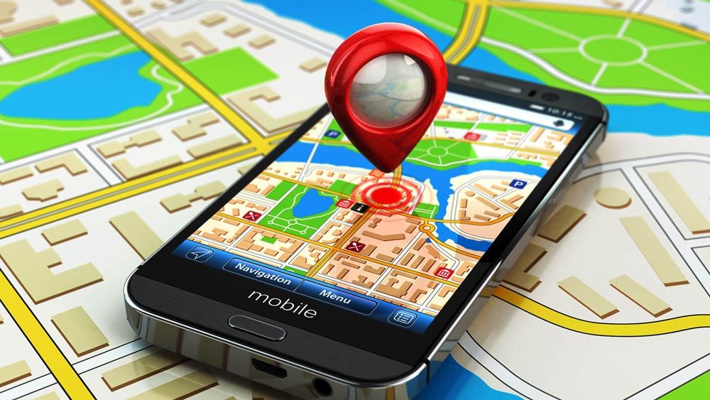A cell phone with a red pin on it is sitting on top of a map.