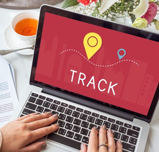 A person is typing on a laptop with the word track on the screen
