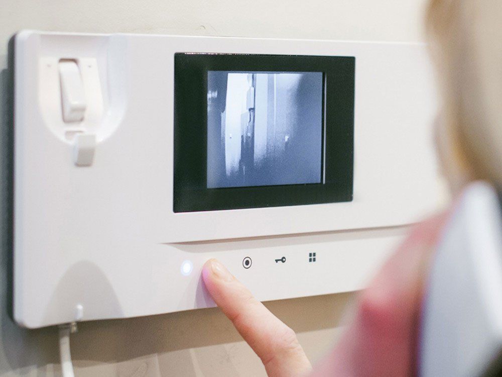 A person is pressing a button on a video doorbell.