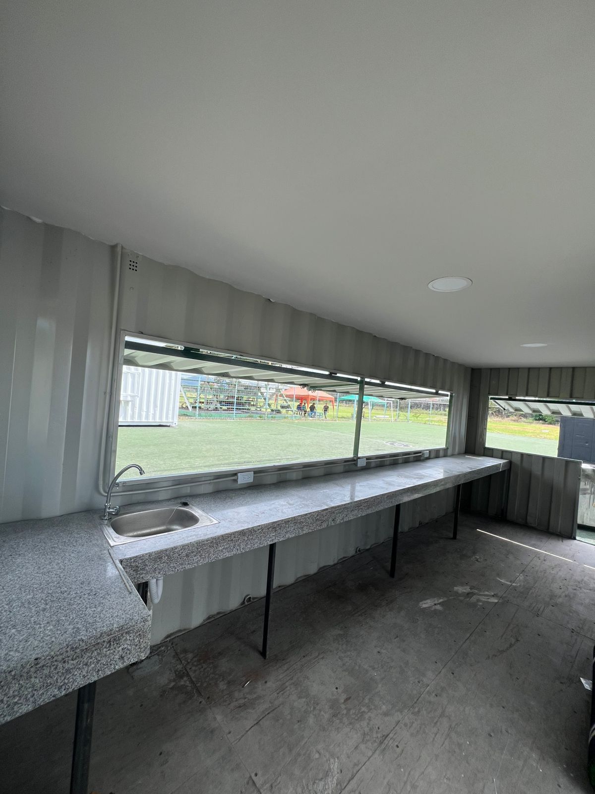 Vista interior de un espacio construido con un contenedor de transporte, que cuenta con una larga encimera de granito