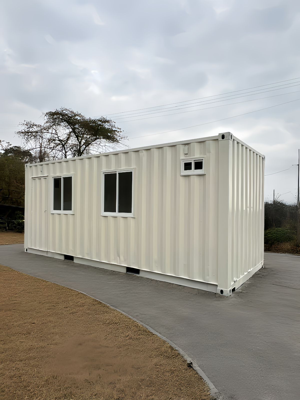 Un contenedor de transporte rectangular de color claro, reconvertido en oficina o estructura con ventanas