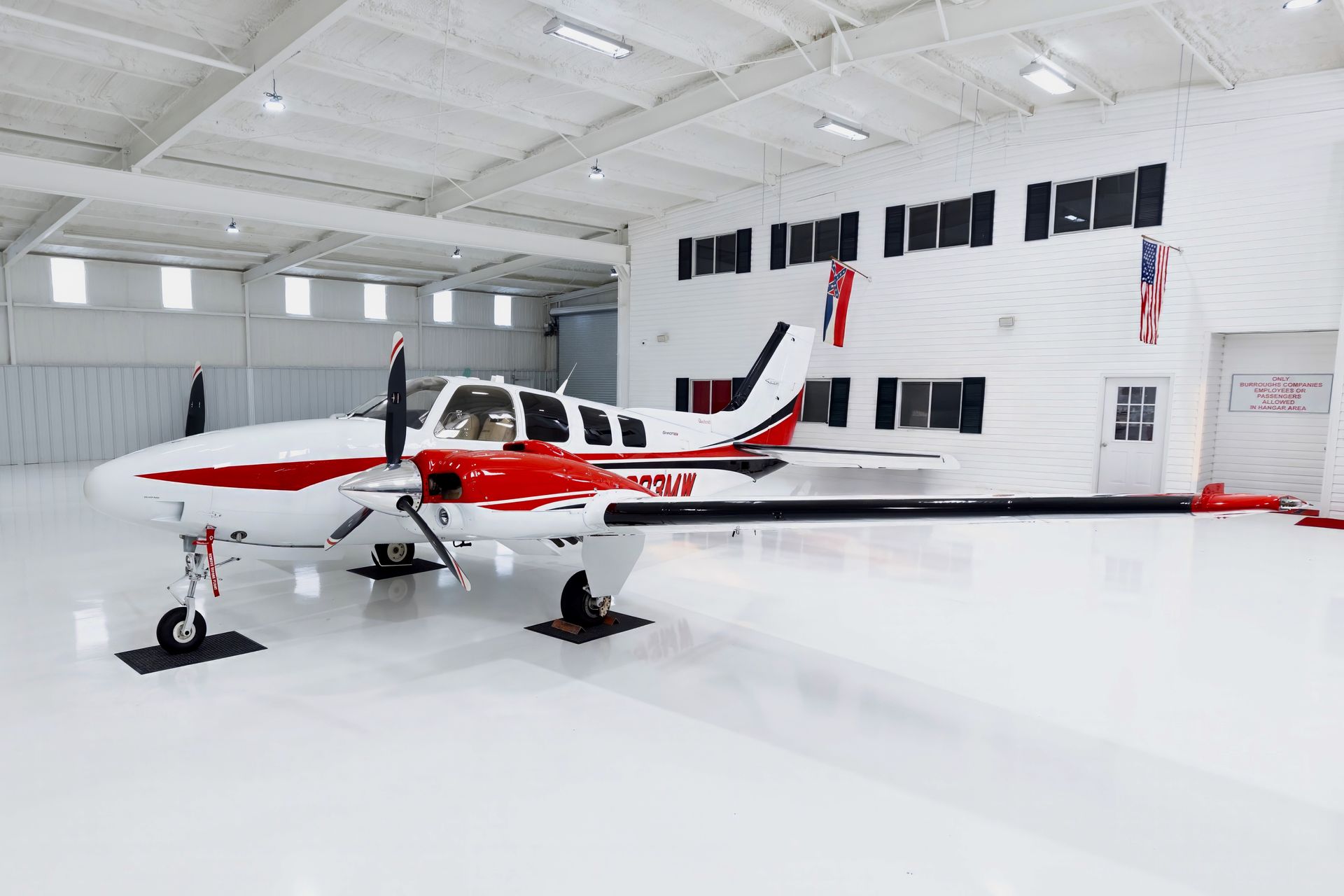White and red airplane inside a white hangar.