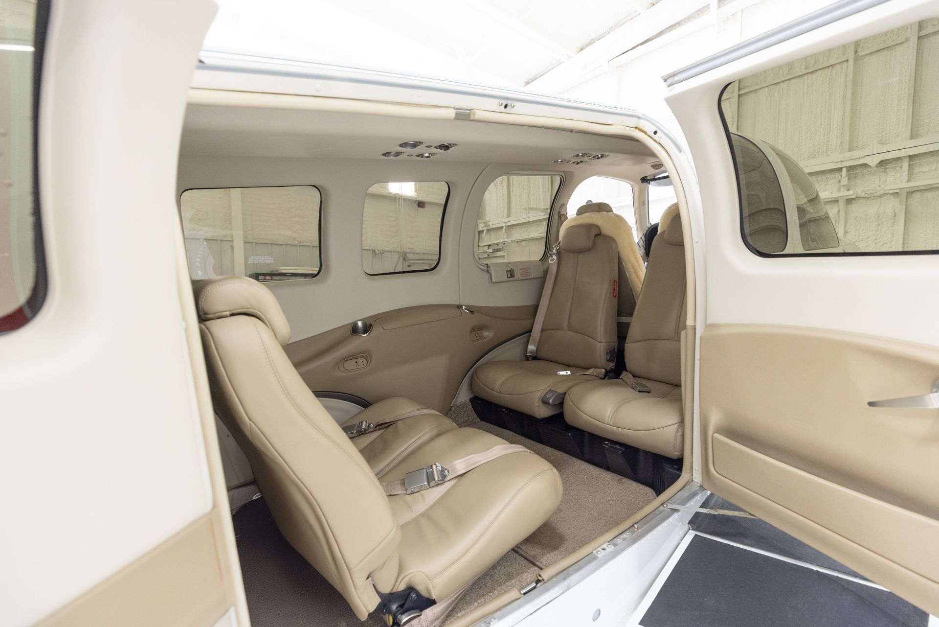 Interior view of a small aircraft with beige seats, windows, and door open.