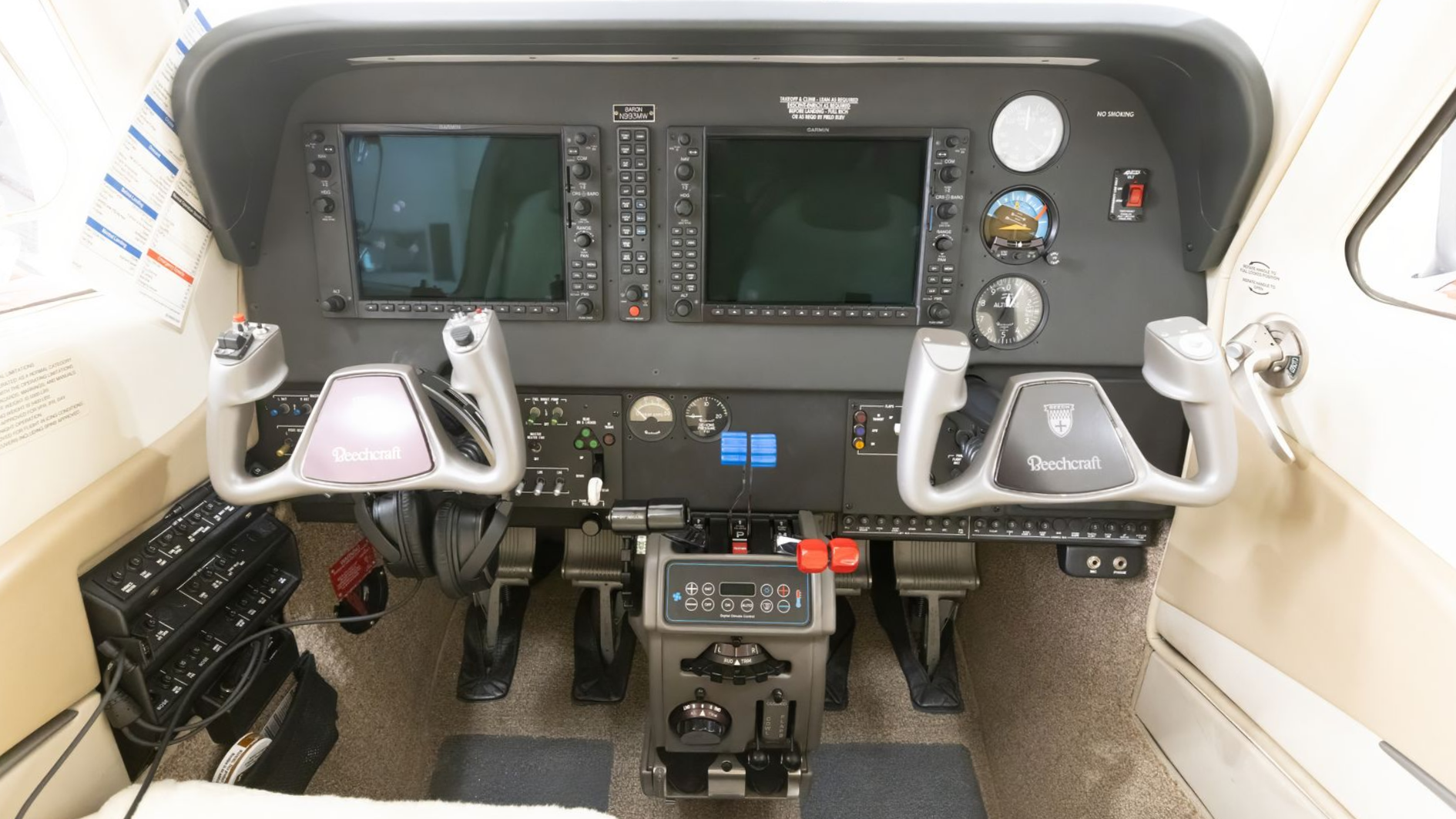 Aircraft cockpit with dual yokes, display screens, and instrument panel.