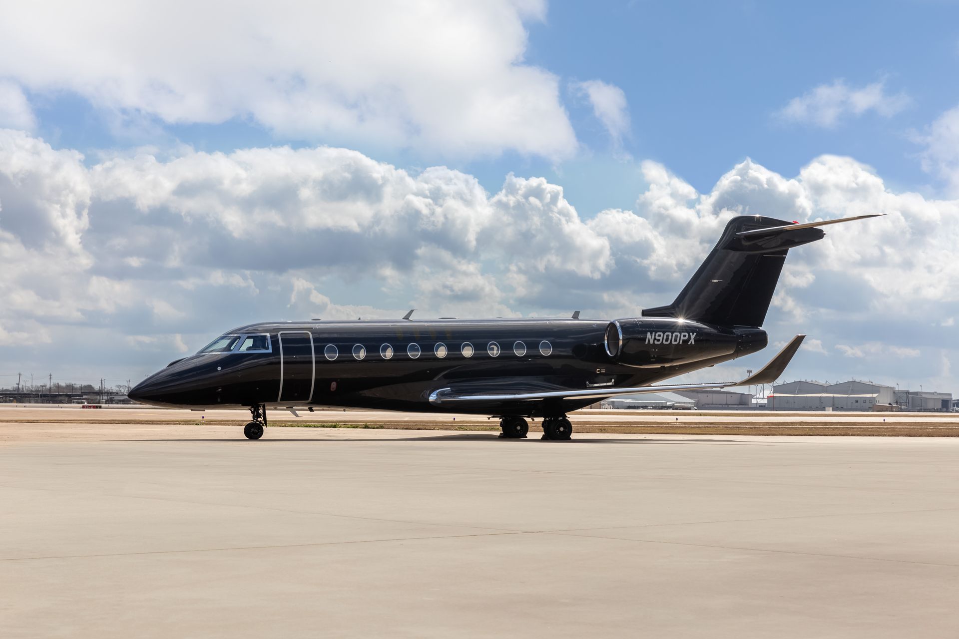 Amjet Aviation Listing; Gulfstream G280; Black private jet on a tarmac under a cloudy blue sky.