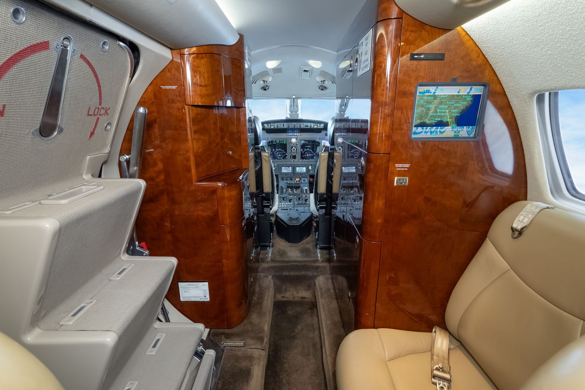 Interior view of a private plane, showcasing the cockpit and seating area with wood paneling.