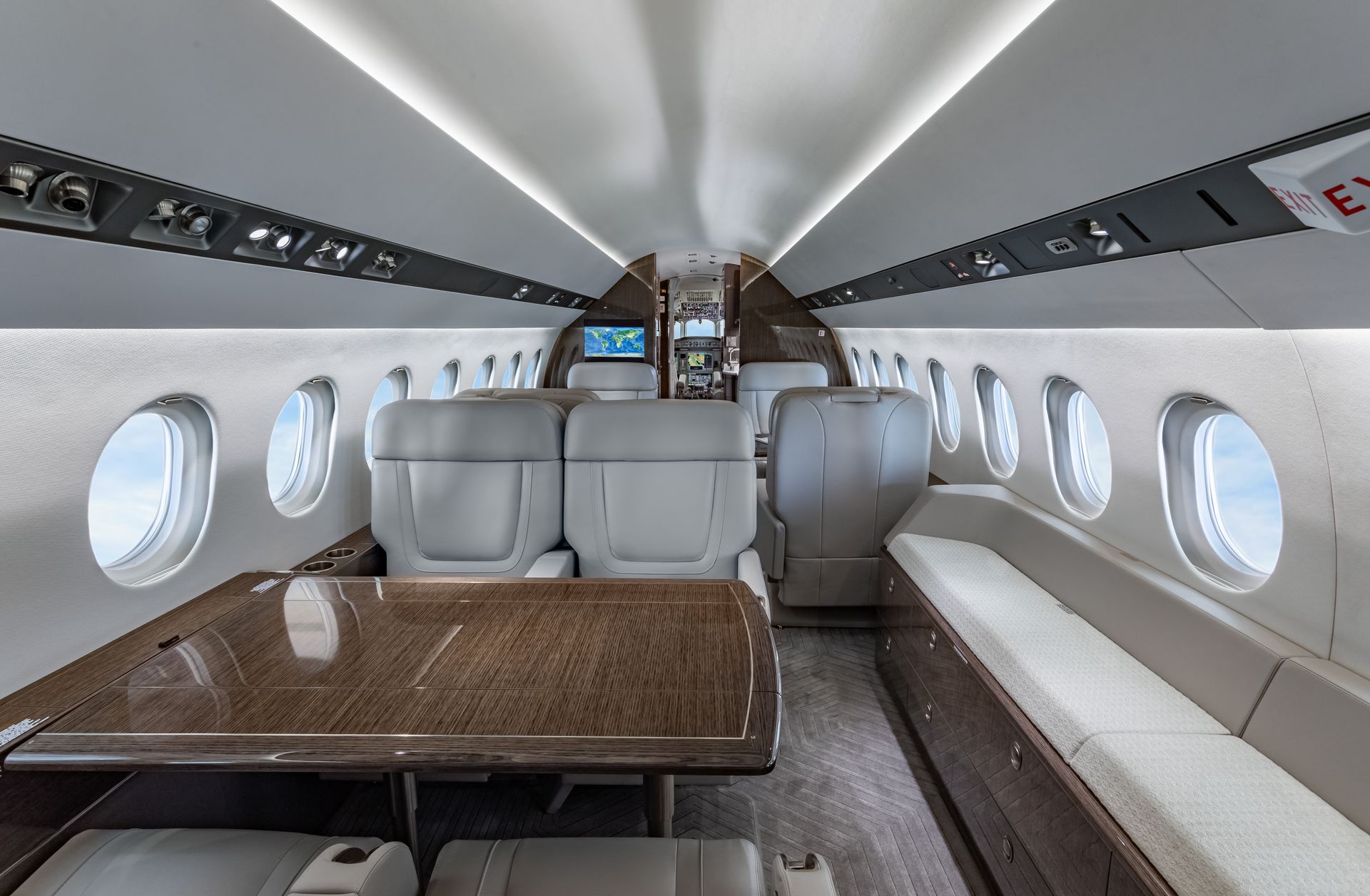Interior view of a private jet cabin, featuring seating, a table, and windows.