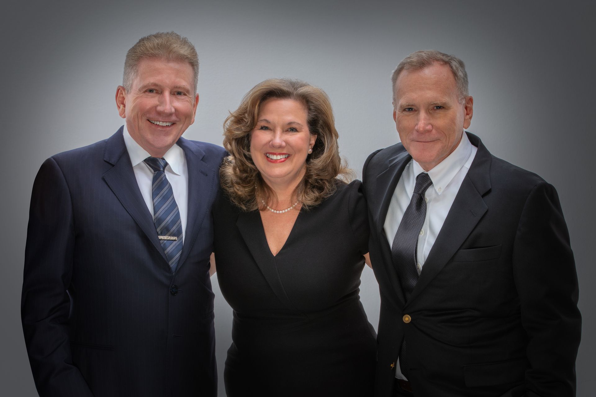 Man working at desk with laptop and mobile phone, city lights in background.