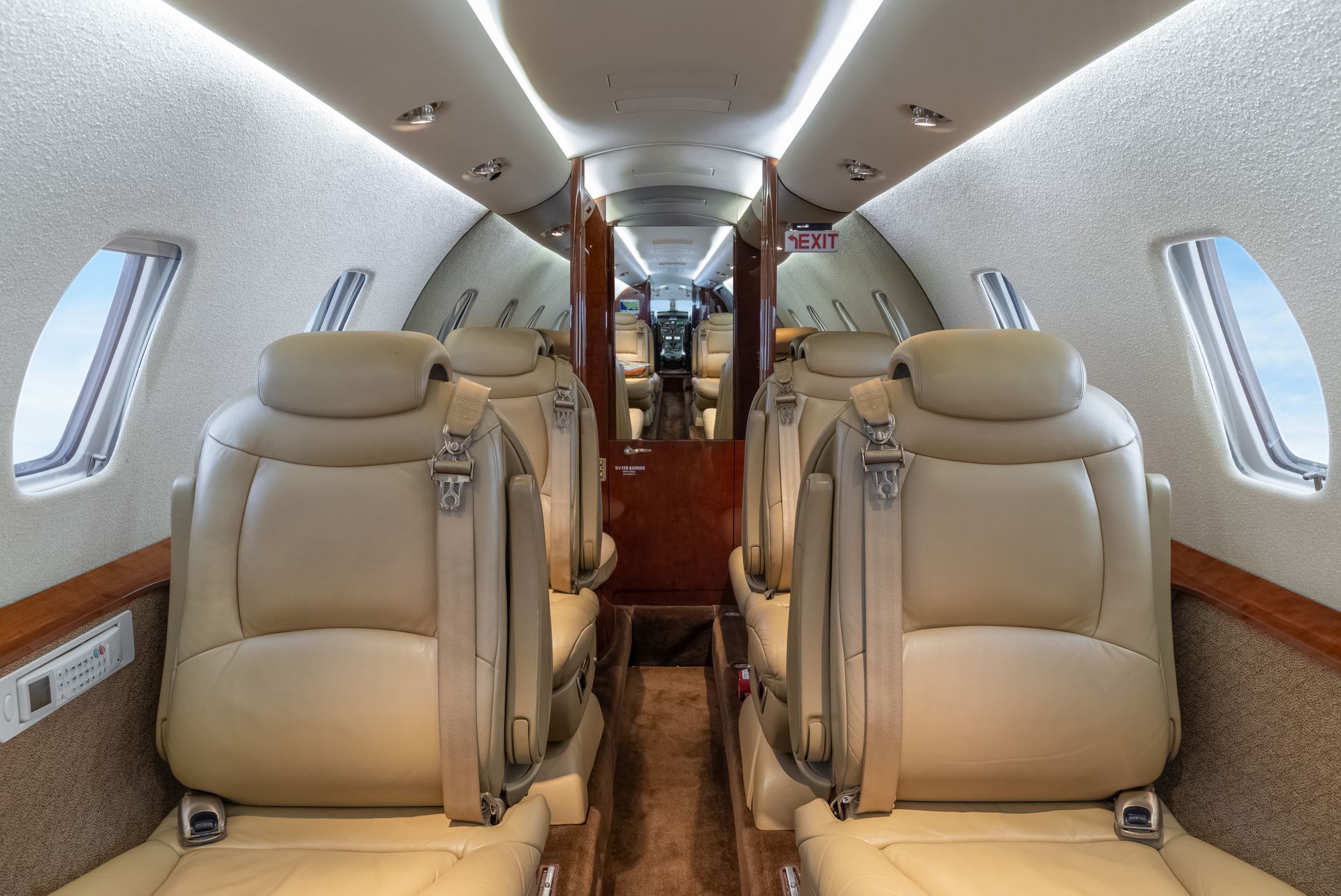 Interior of a private jet with beige leather seats and wood paneling.