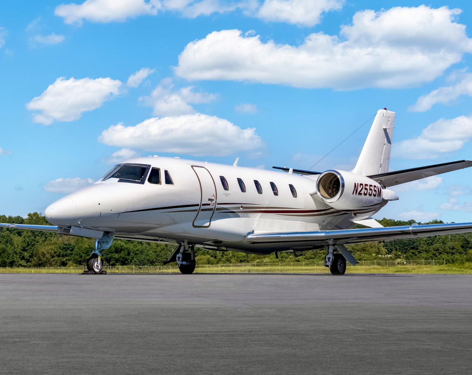 White Citation XLS+ private jet on a gray runway against a blue sky with clouds.