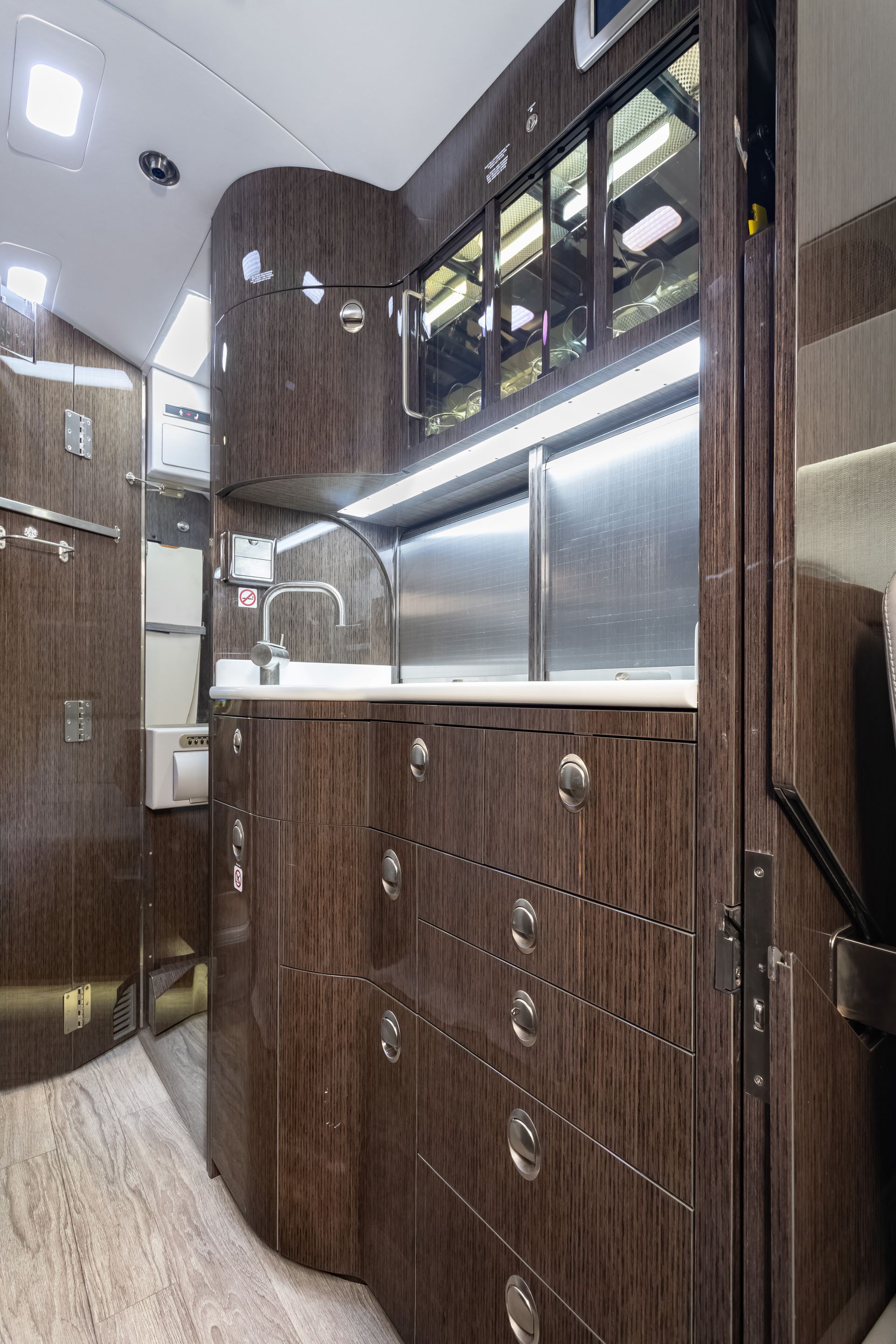 Dark wood cabinetry and sink in a luxurious private jet galley.