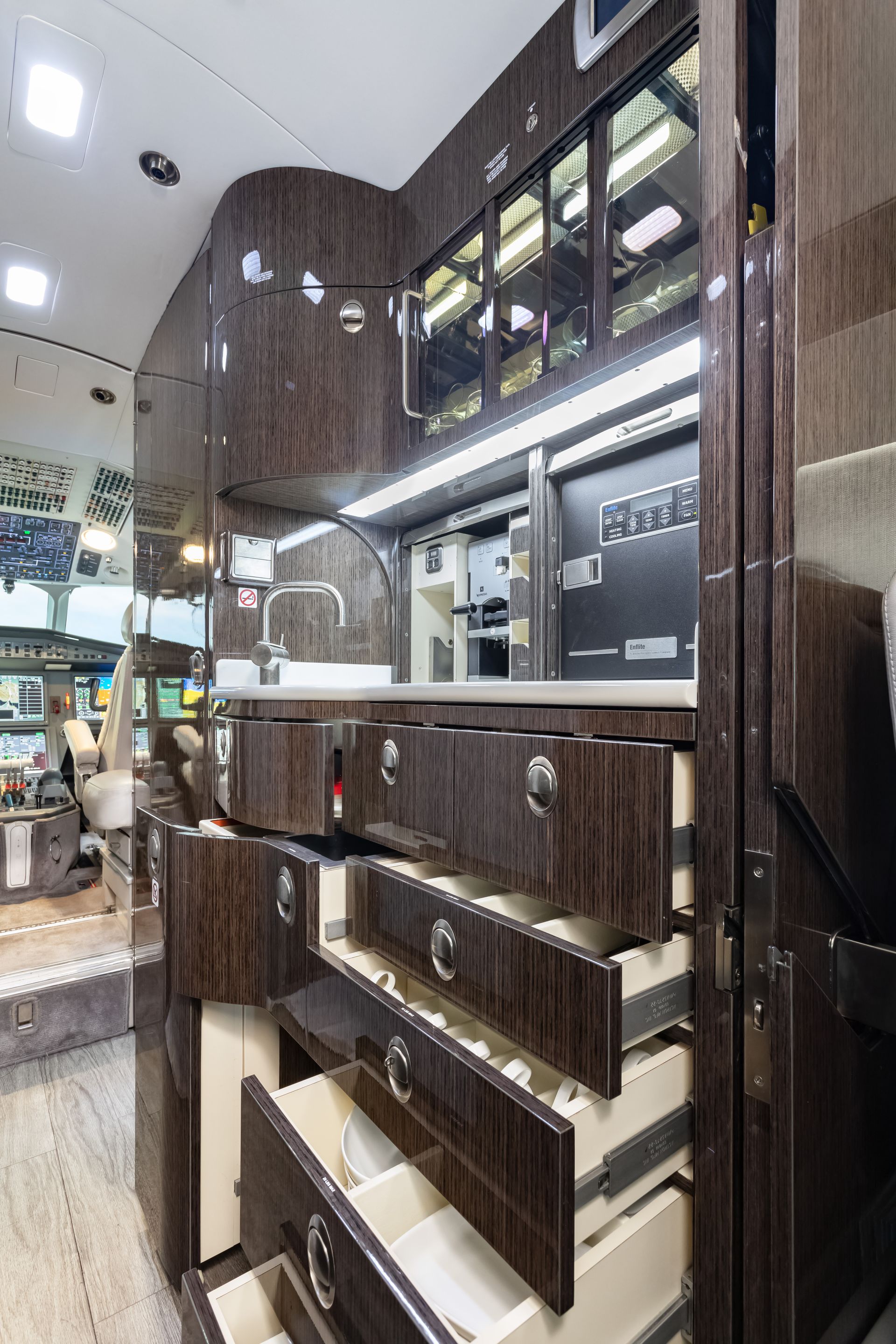 Interior of a luxury vehicle featuring dark wood cabinetry, drawers, and a built-in sink.