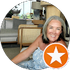 A woman is sitting in a living room with a star in an orange circle.