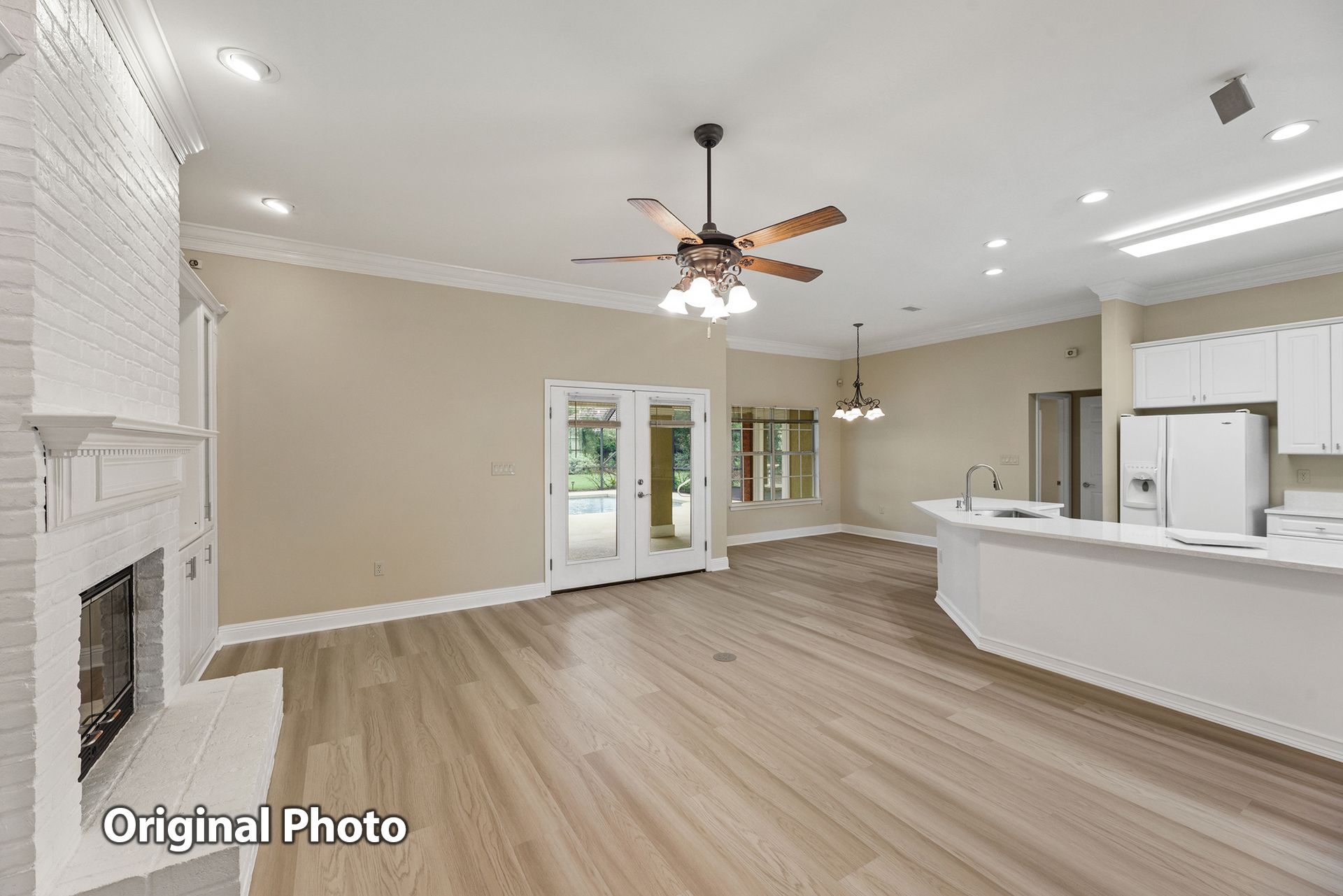 An empty living room with hardwood floors and a ceiling fan. No virtual staging.