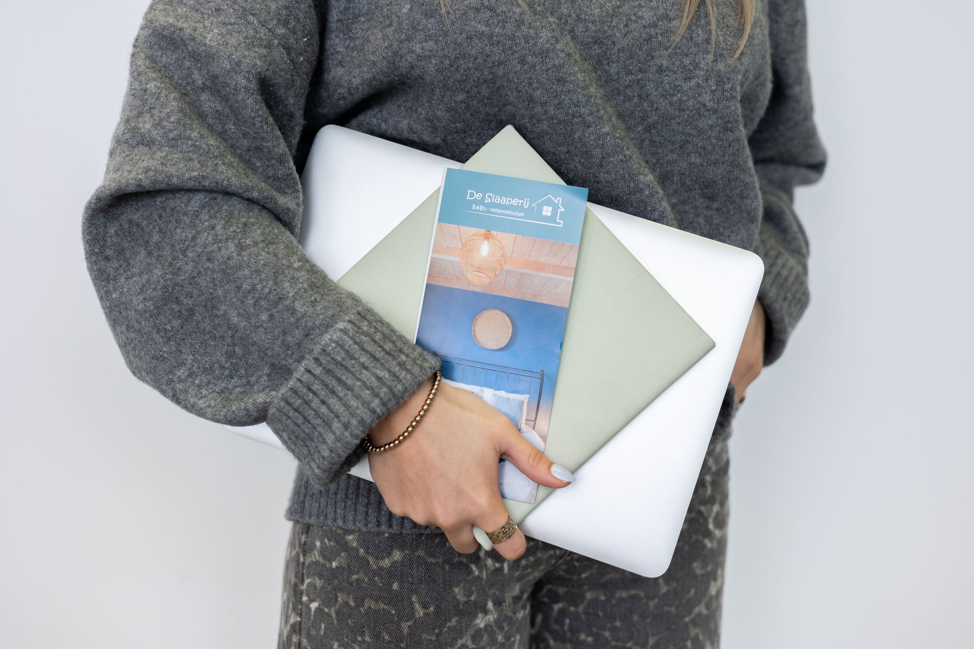 Een vrouw houdt een laptop en een tijdschrift in haar handen.