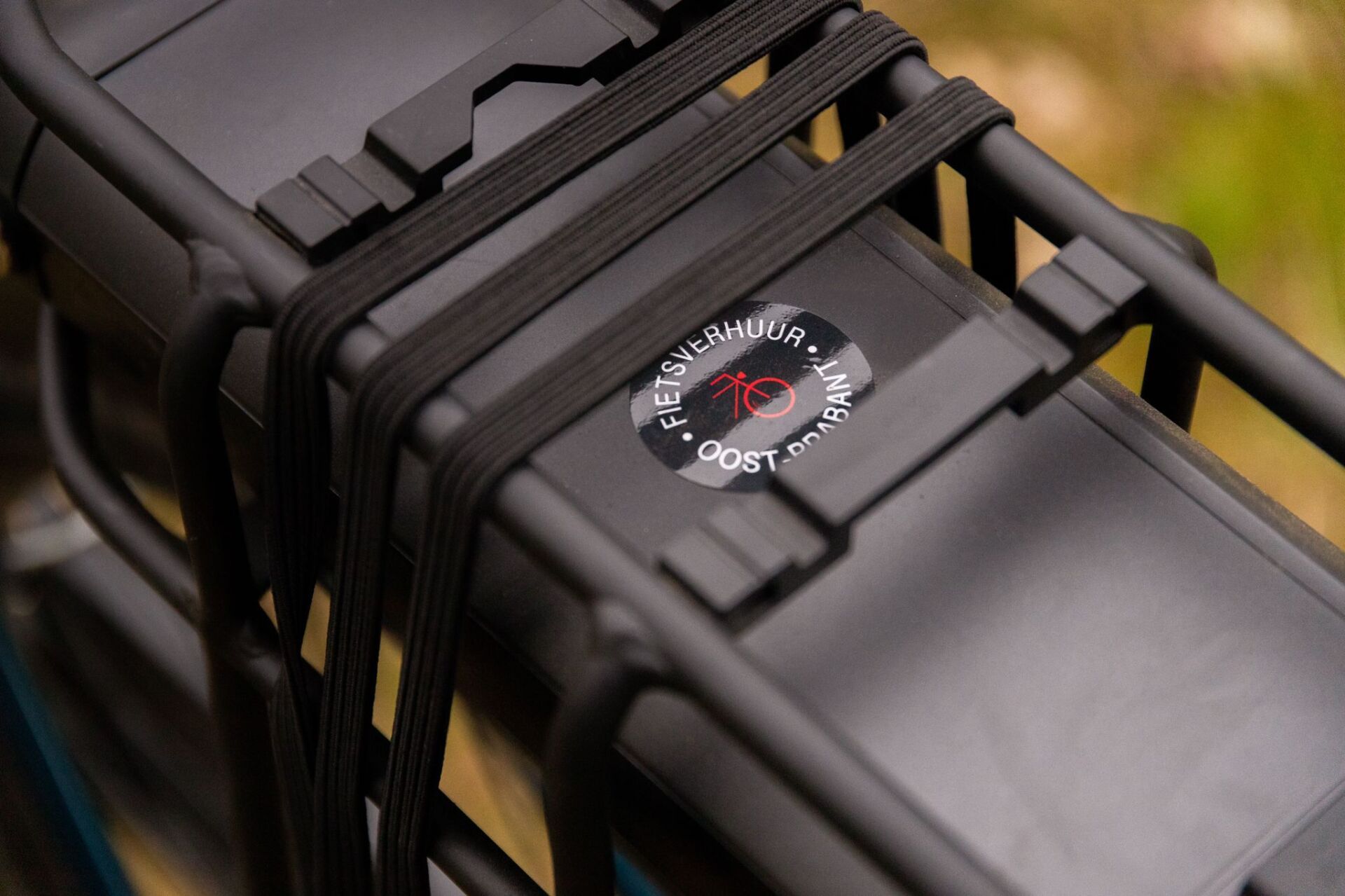 Een zwarte accu is bevestigd aan de achterkant van een fiets.