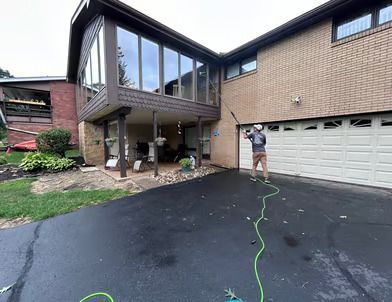 A man is cleaning the windows of a large brick house.