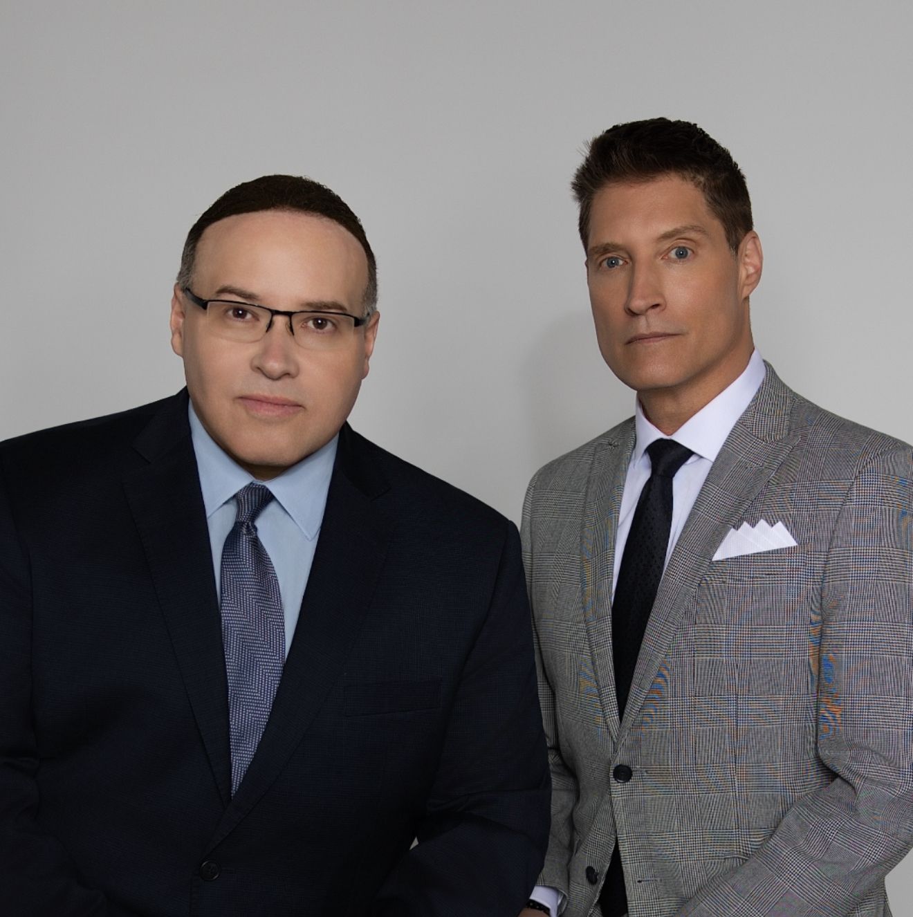 Man in suit holding a soccer ball while wearing goalie gloves.