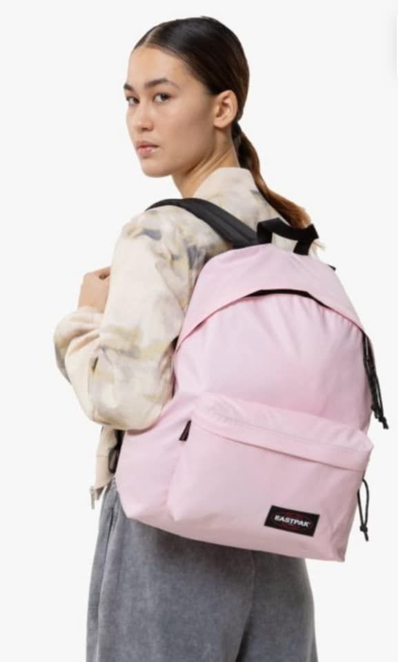 Una donna porta uno zaino rosa sulla schiena.