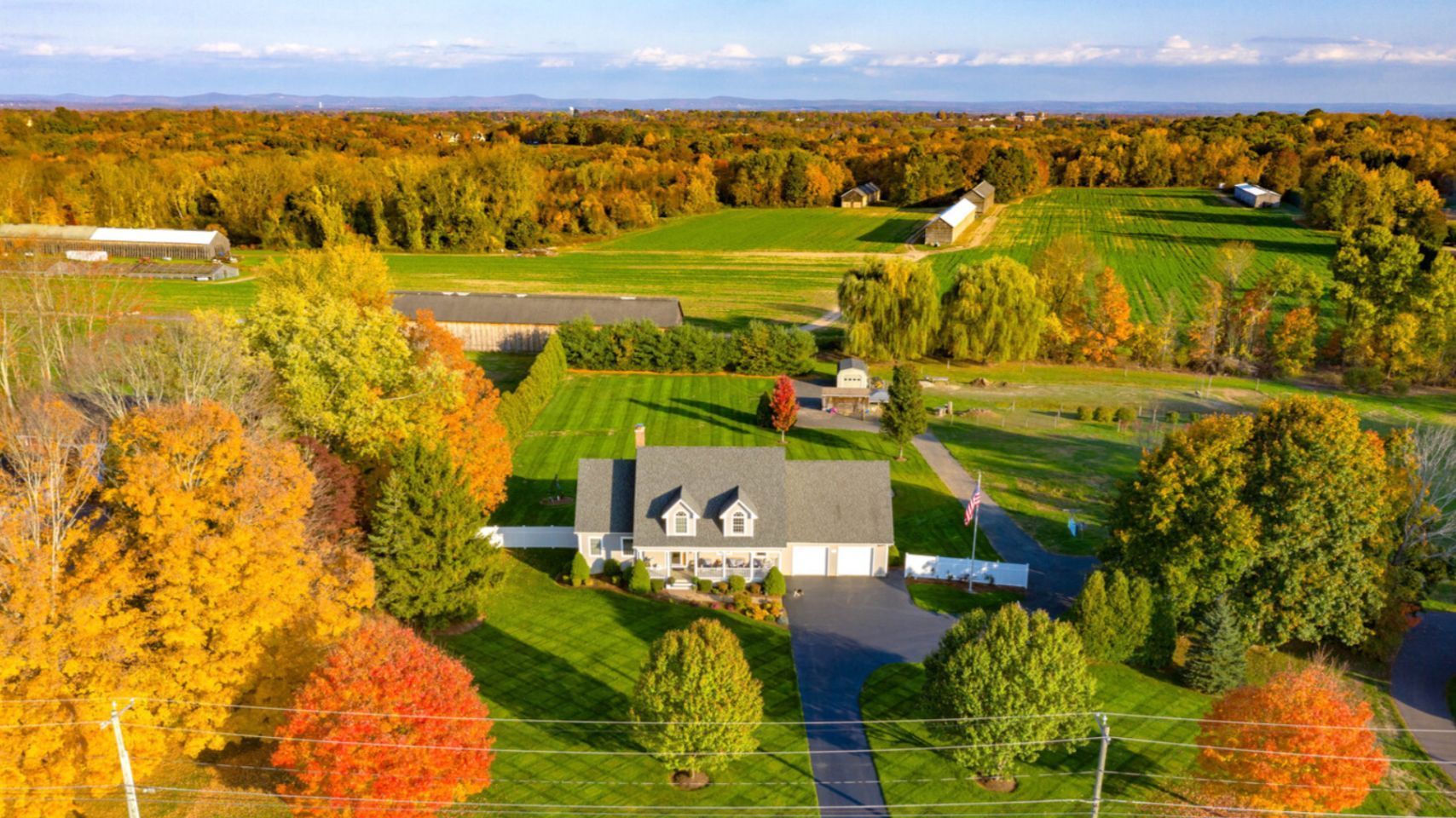 An aerial view of a house in the middle of a lush green field surrounded by trees.