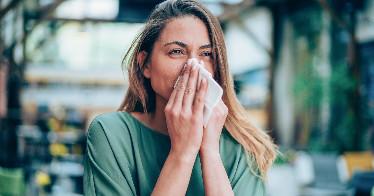 A woman is blowing her nose into a napkin due to allergies.