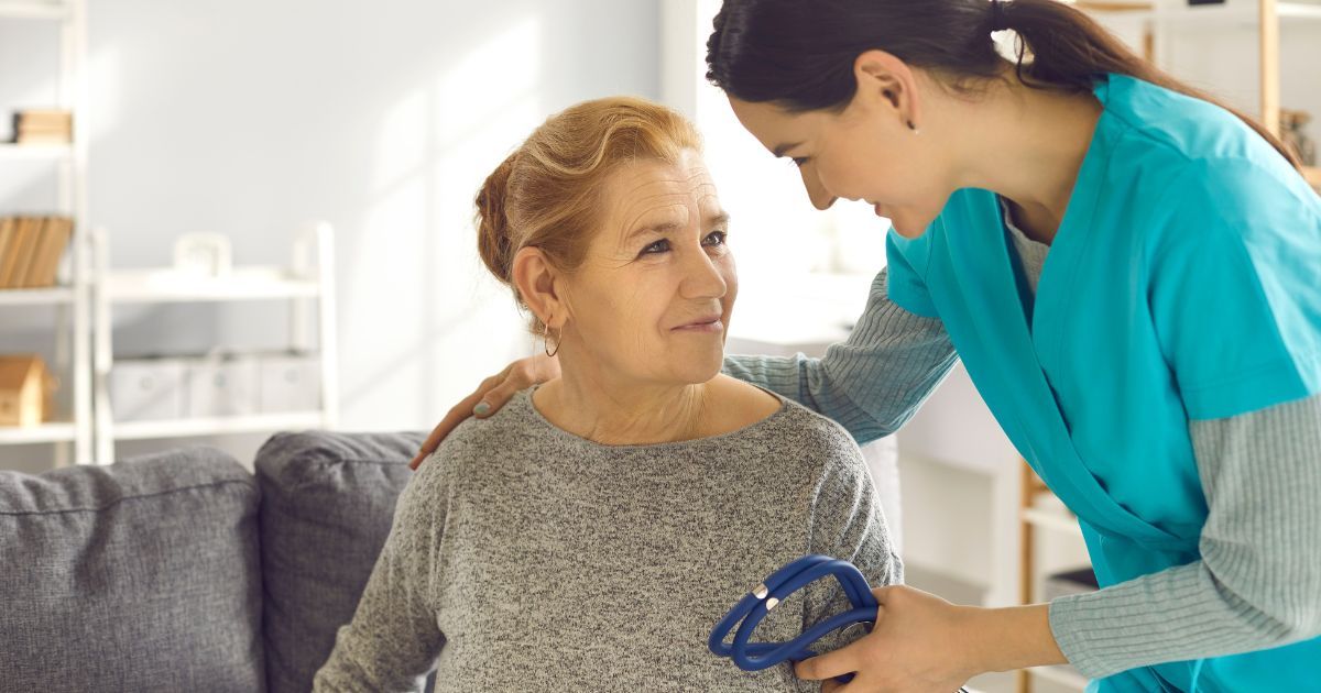 A nurse is helping an elderly woman in a wheelchair.