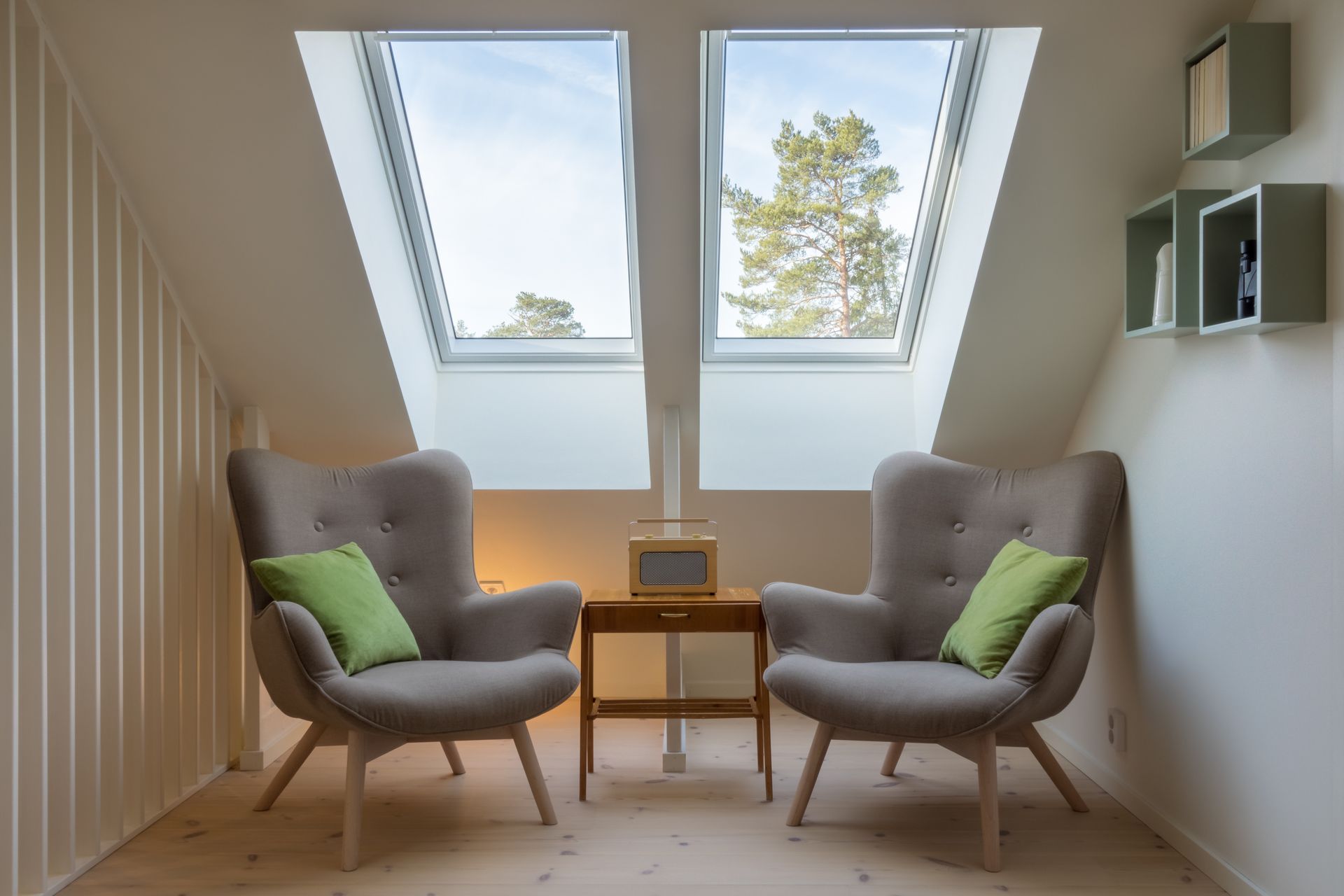 A small vintage table with a radio on and two reading chairs under two skylights.